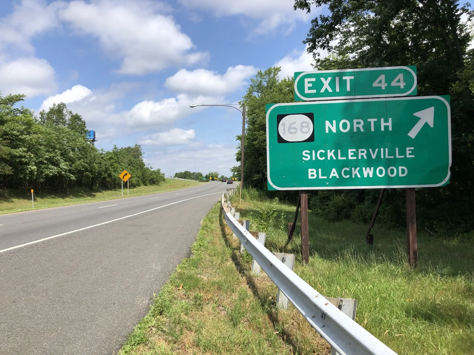 The Atlantic City Expressway westbound at Exit 44 for Route 168, Sicklerville and Blackwood, two lanes between trees