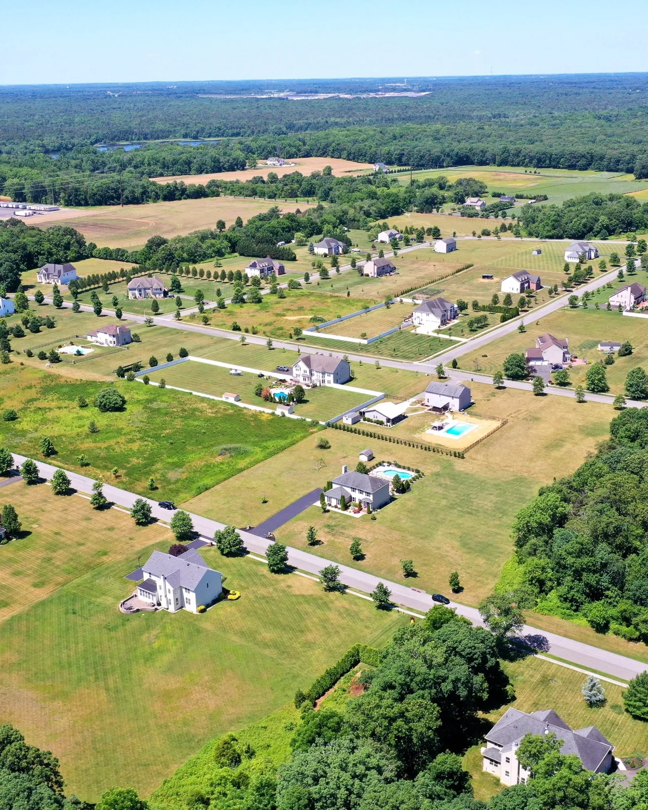 An aerial view of new single family homes set on large lots among farm fields and woods