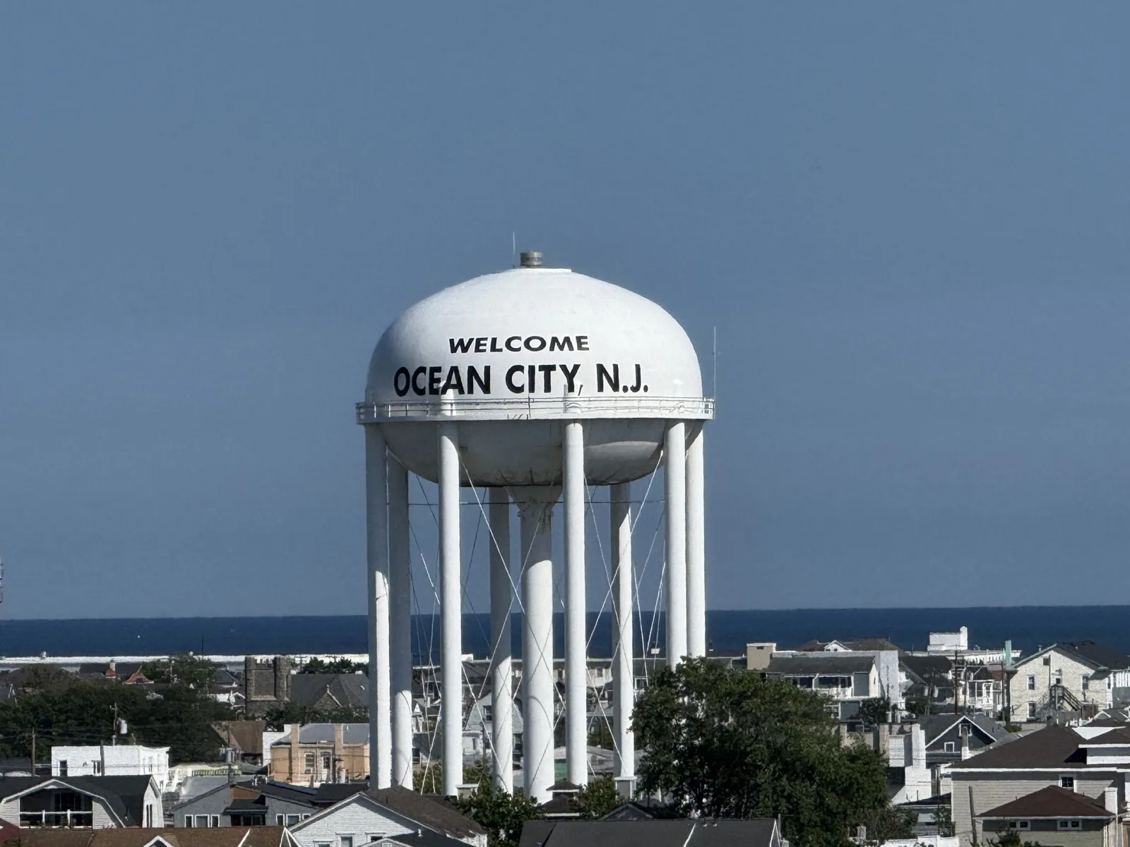 The Ocean City NJ water tower rising over homes, with the ocean behind