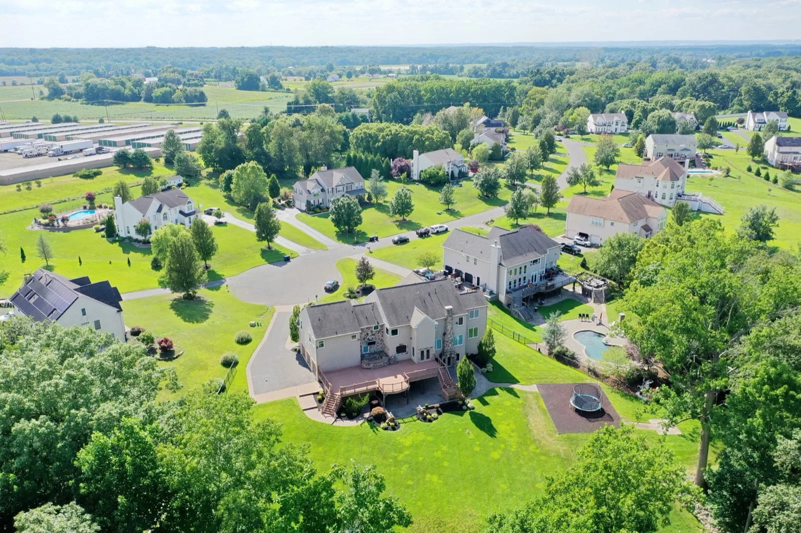 Aerial view of an established South Jersey community of large homes with open ground beyond on a summer day