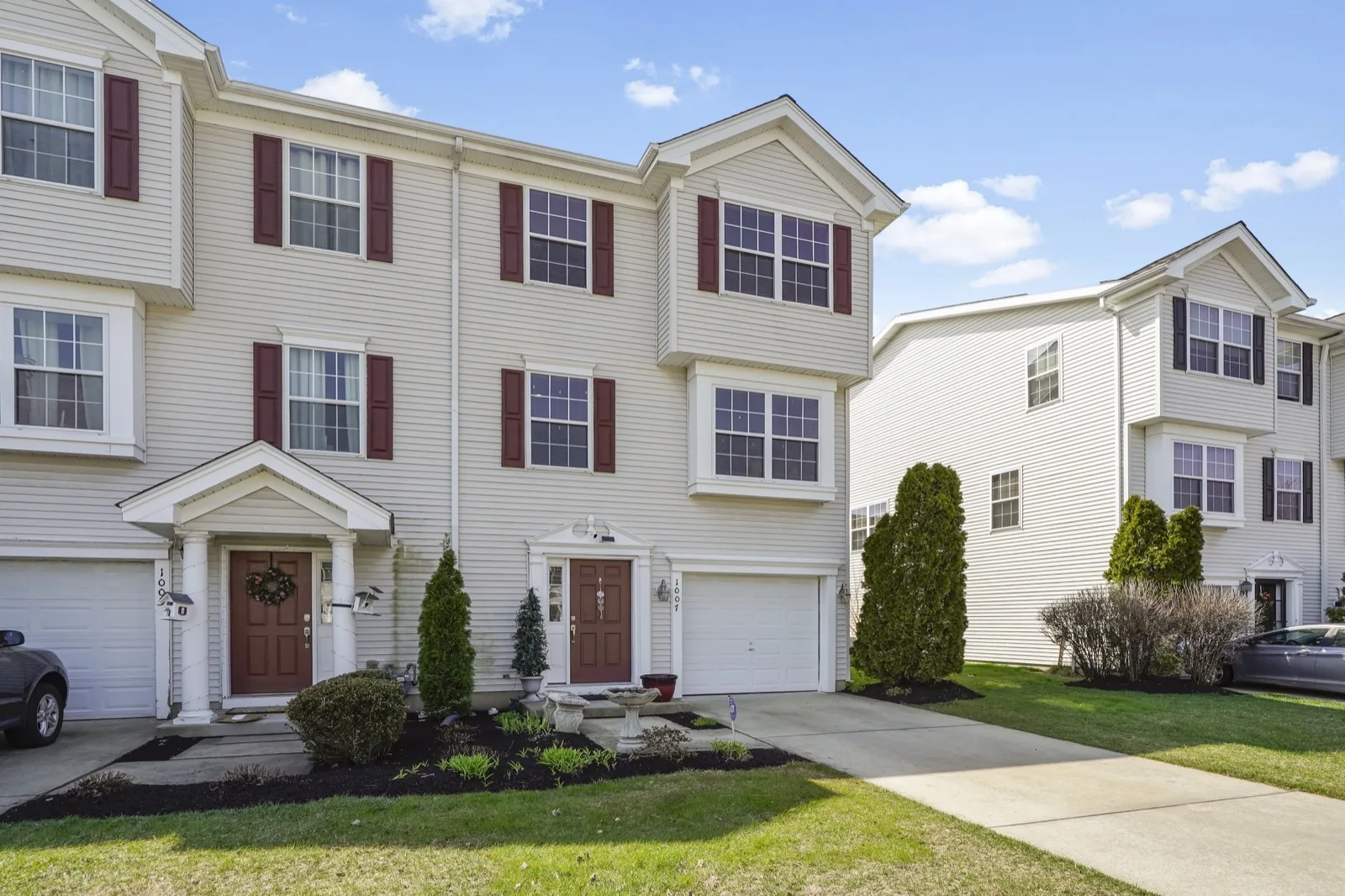 A row of three story attached townhomes with front garages and small planted beds