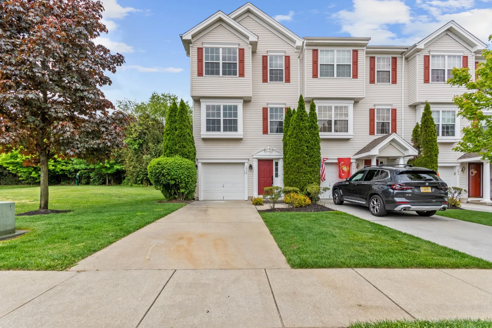 A three story attached townhome with a front garage, seen from the end of its front walk