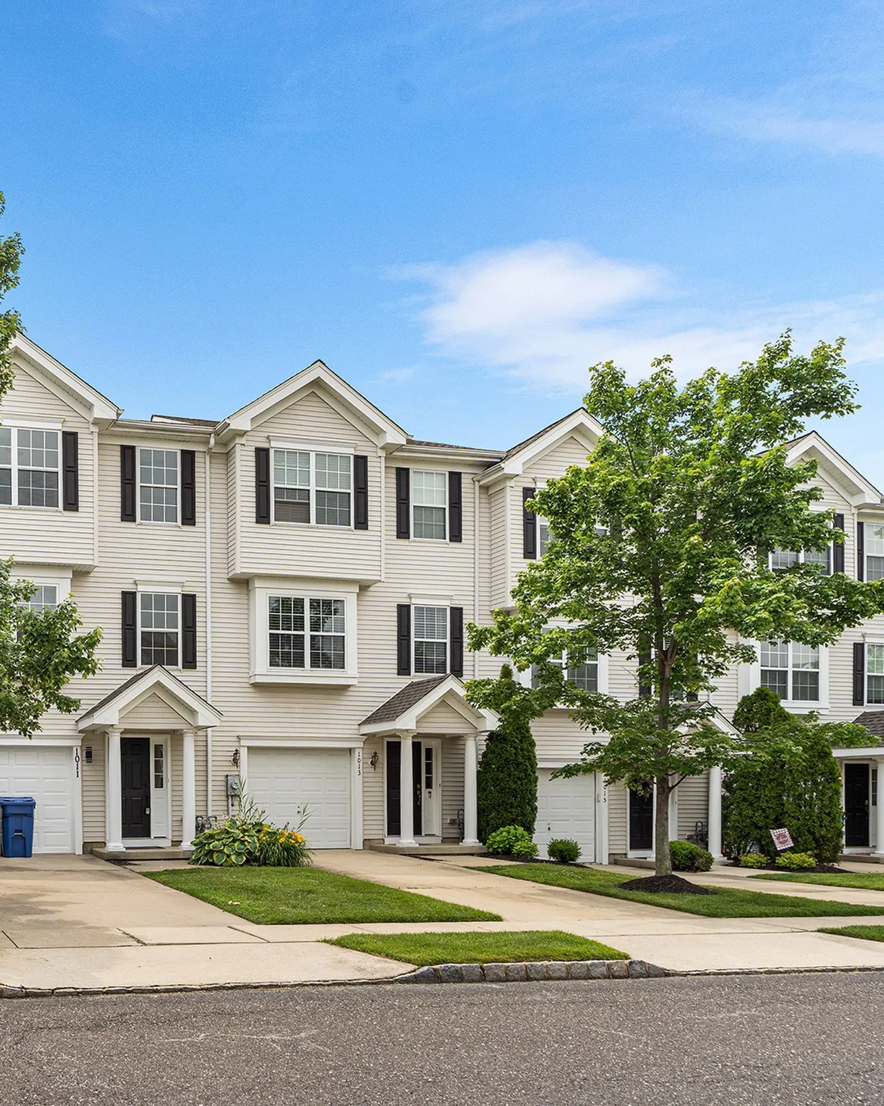 A street of new attached townhomes with one car garages and covered front doors